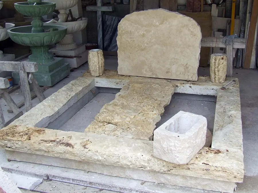 Rusztikus dupla mészkő sírkő természetes fejkővel és kővázákkal, műhelyben készítés közben