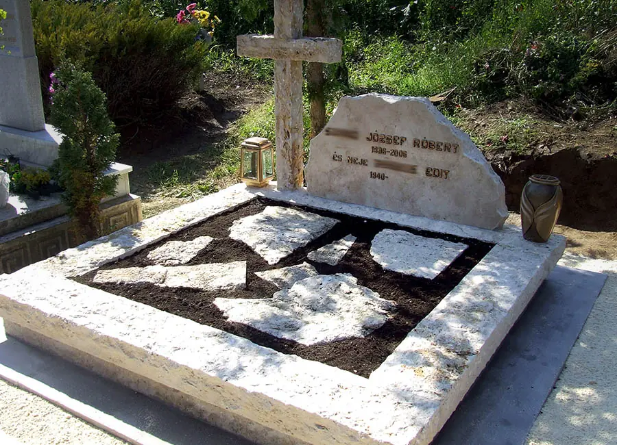 Nyitott dupla mészkő sírkő rusztikus fejkővel, faragott kereszttel és kőlapokkal