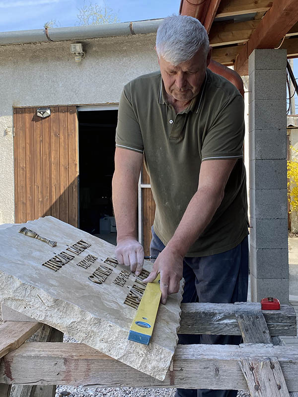 Rest István sírkő feliratot ellenőriz vízmértékkel a műhelyben